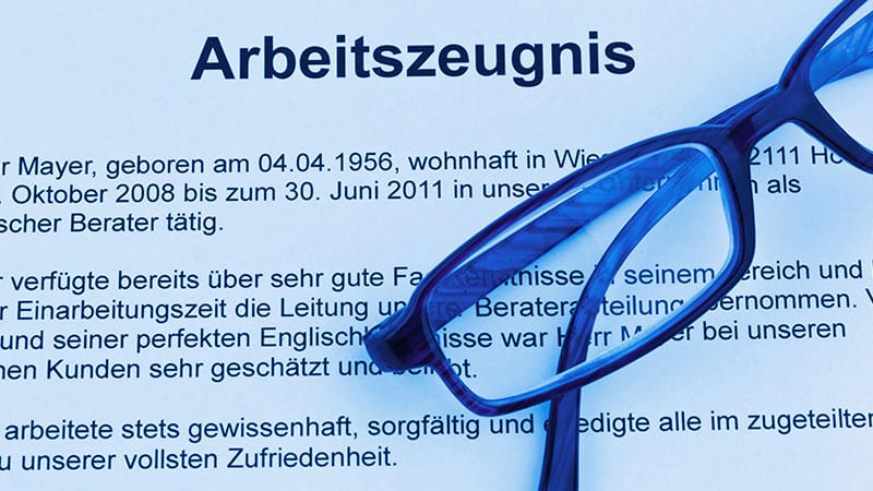 Eine Brille liegt auf einem Arbeitszeugnis, von dem der obere Teil des Textes lesbar ist.