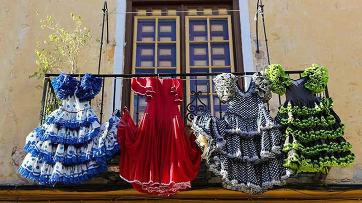 Vor einem spanischen Haus hängen mehrere traditionelle Flamenco-Kleider.