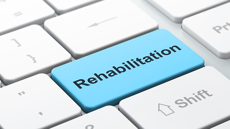 Auf einer Tastatur steht auf einer Taste das Wort Rehabilitation.