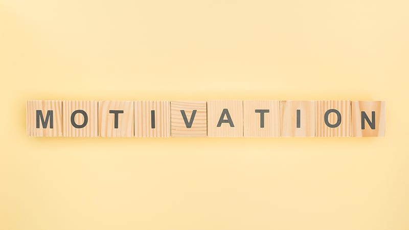 Auf zusammengesetzten Holzklötzchen mit je einem Buchstaben entsteht das Wort Motivation.