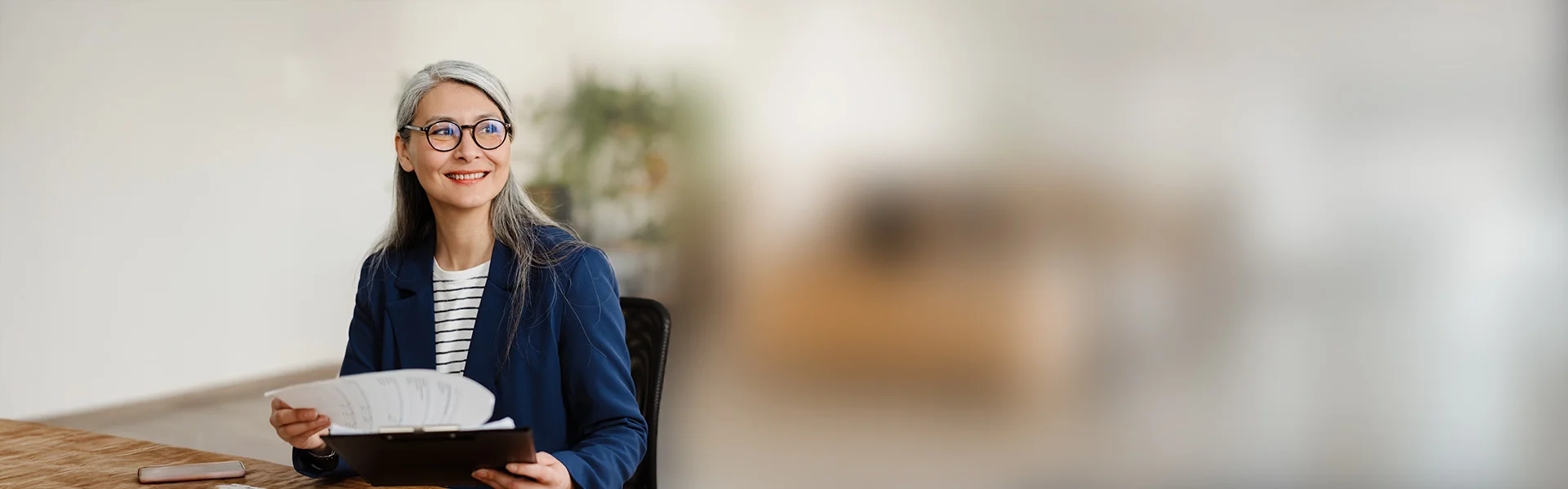eine Frau in der Brille sitzt an einem Schreibtisch mit einem Buch