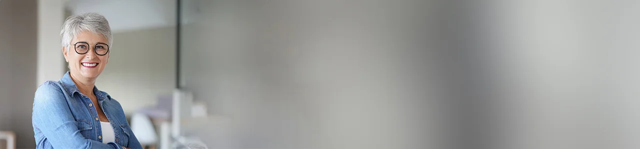 eine Frau mit grauem Haar und Brille lächelt