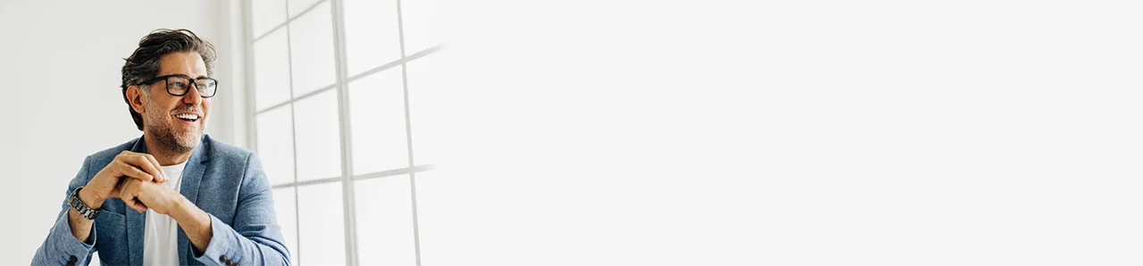 ein Mann in einem blauen Hemd und einer Brille, die an einem Fenster steht