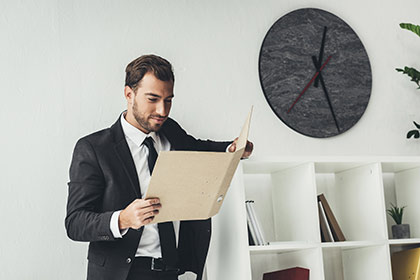 Mann mit Ordner in der Hand liest etwas über die Bildungsprämie bei geförderter Weiterbildung