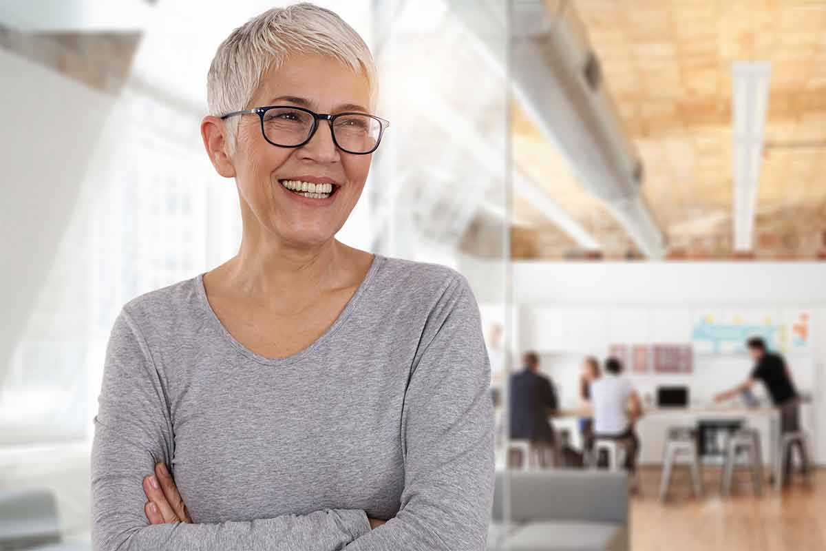 eine Frau mit Brille lächelnd in einem Büro