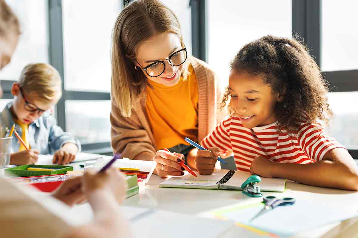 eine Gruppe von Kindern, die um einen Tisch sitzen, zeichnend