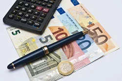 ein Taschenrechner und ein Stift auf einem Haufen Geld