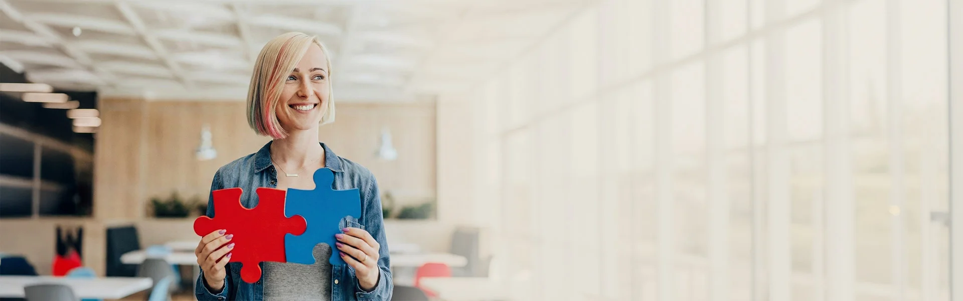 Eine Frau mit Puzzleteilen guckt freundlich in die Kamera