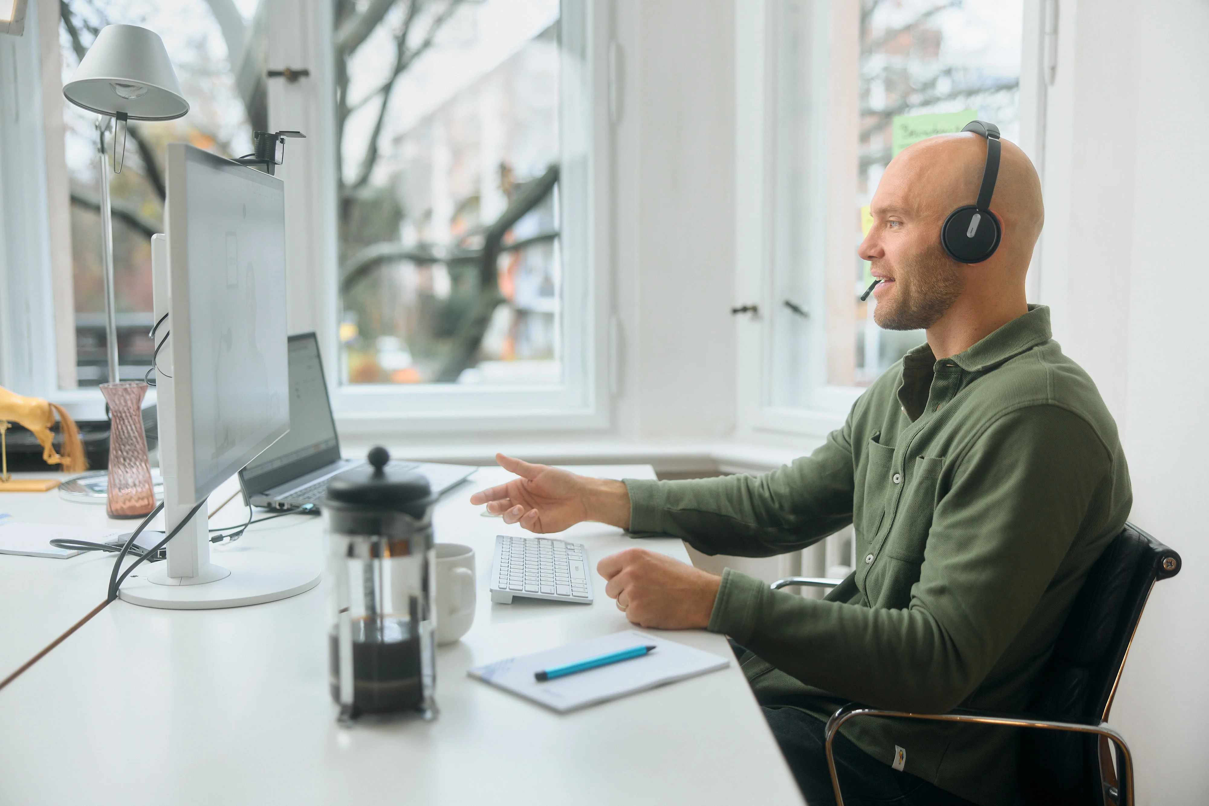 Ein Mann ohne Haare sitzt am Computer mit einem Headset