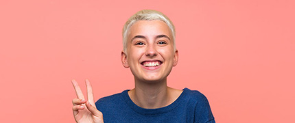 Jetzt zu den Top-10-Umschulungen beim IBB informieren! Frau lächelt und zeigt ein Peace-Zeichen. Sie ist glücklich mit ihrer Umschulung.