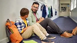 Ein Mann und ein Junge sitzen auf dem Boden und sprechen miteinander