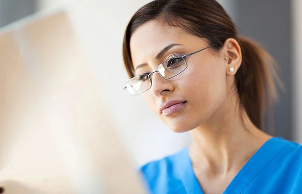 eine Frau in einem blauen Peeling Anzug und Brille Blick auf einen Computer-Bildschirm