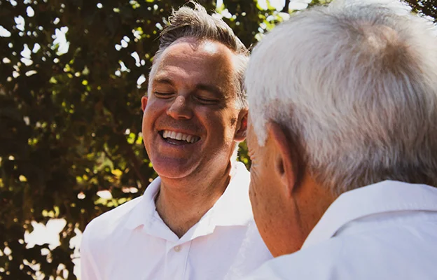 ein Mann trägt ein weißes Hemd und zeugt einem Kunden etwas auf einem Laptop