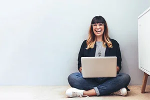 eine Frau, die mit ihrem Laptop auf dem Boden sitzt