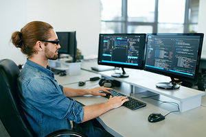 Junger Mann sitzt am Computer und macht Softwareentwicklung