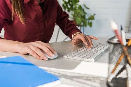 Frau sitzt vor einem Computer an der Tastatur und denkt über eine Weiterbildung für ICDL Powerpoint Präsentationen nach