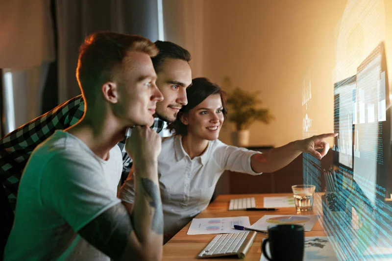 Drei Personen sitzen vor einem innovativen Bildschirm.