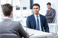 zwei Männer in Anzügen sitzen an einem Tisch