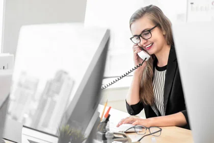 eine Frau, die an einem Schreibtisch sitzt und am Telefon spricht