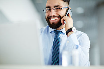 Fachwirt für Vertrieb im Einzelhandel Junger Man sitzt mit einem Telefon vor dem Laptop