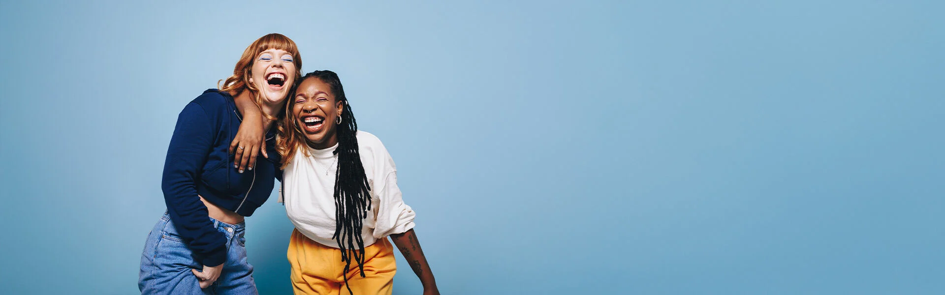 Zwei junge Frauen umarmen sich lachend