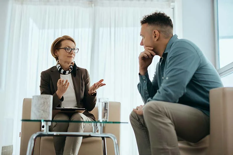 Frau mit Brille erklärt einem Mann gestikulierend etwas.