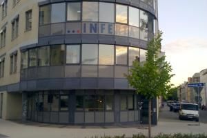 ein modernes Gebäude mit vielen Fenstern und einem grünen Baum davor