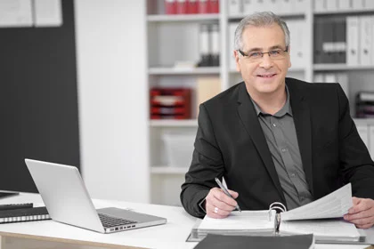 ein Mann sitzt an einem Schreibtisch mit einem Laptop und Papieren