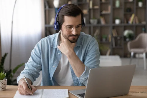 ein Mann trägt Kopfhörer während der Arbeit an einem Laptop