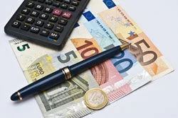 ein Taschenrechner und ein Stift auf einem Haufen Geld