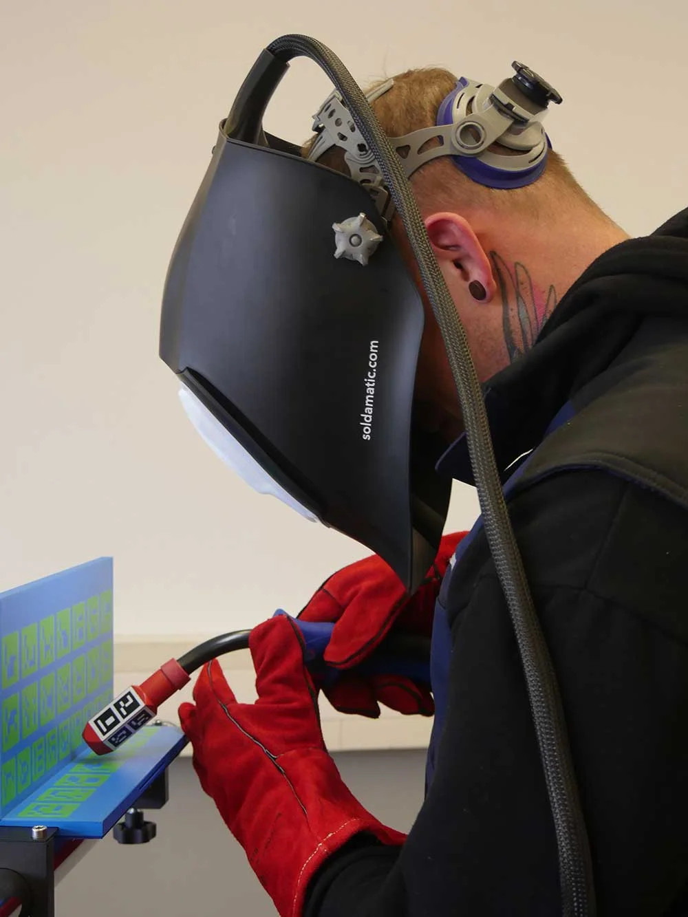ein Mann trägt eine Maske und Handschuhe während der Verwendung eines Schweißgerätes
