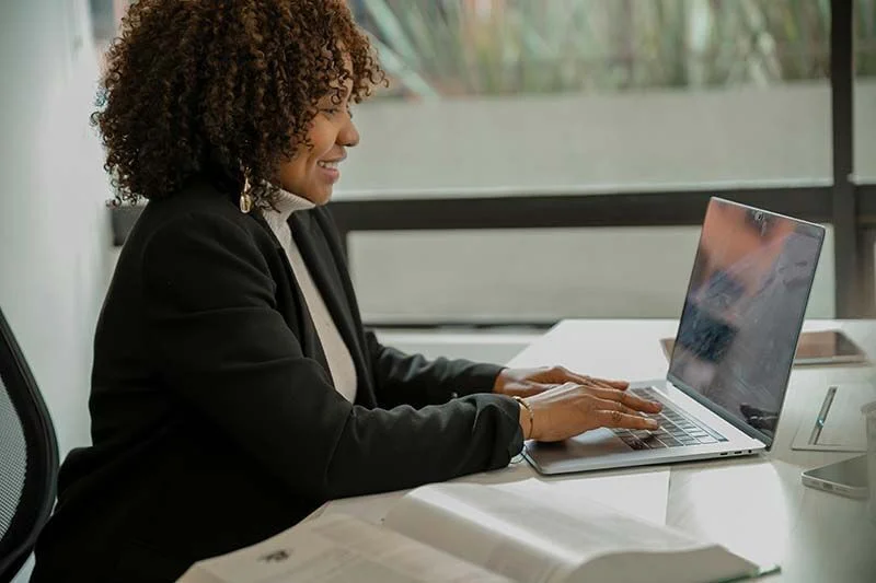 Frau mit Locken sitzt vor dem Laptop und lernt.