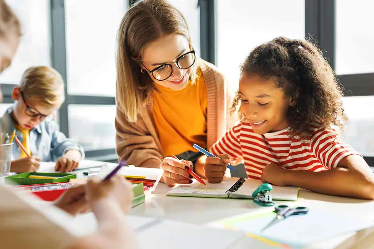 eine Gruppe von Kindern, die um einen Tisch sitzen, zeichnend